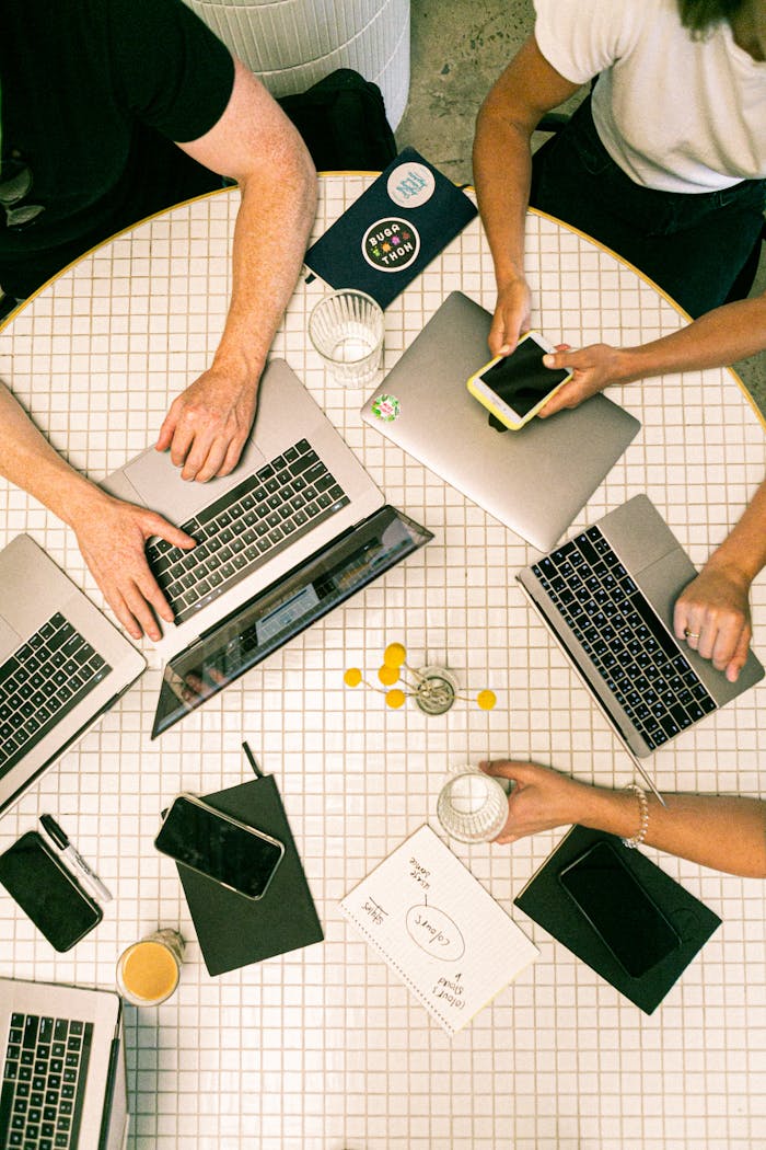 our-story Top view of a team collaborating with laptops, phones, and notes in a modern office.